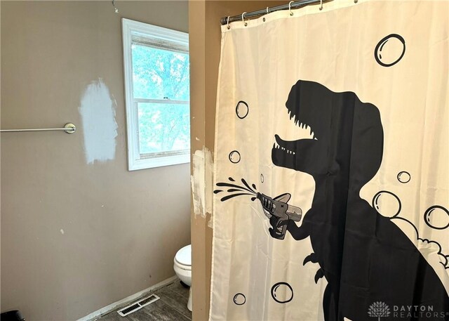 bathroom with walk in shower, hardwood / wood-style floors, and toilet