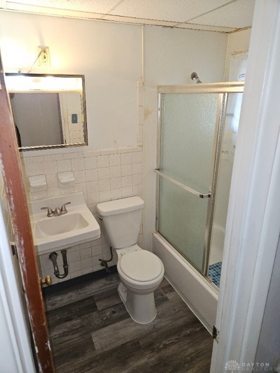 full bathroom with wood-type flooring, tile walls, shower / bath combination with glass door, sink, and toilet