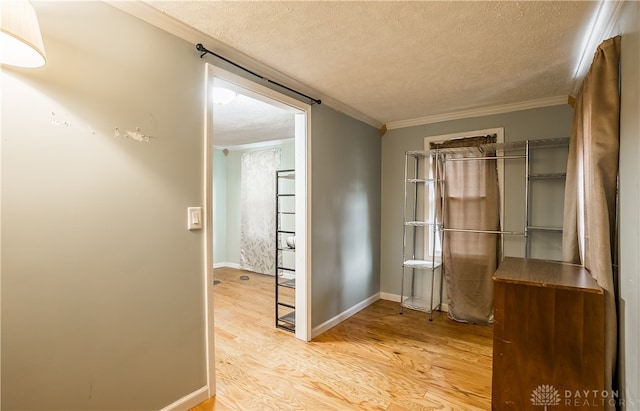 hallway featuring crown molding, a textured ceiling, and light hardwood / wood-style floors