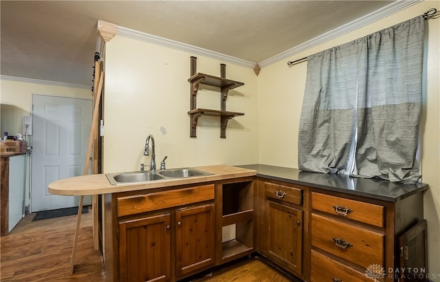 kitchen with sink, a textured ceiling, kitchen peninsula, crown molding, and dark hardwood / wood-style floors