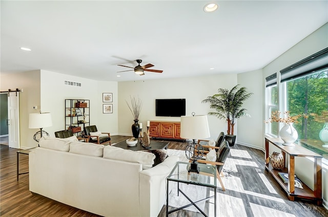 living room featuring a barn door, ceiling fan, and dark wood-type flooring