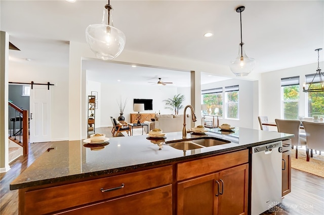 kitchen featuring a barn door, sink, hanging light fixtures, and stainless steel dishwasher