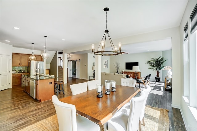 dining space featuring a barn door, a chandelier, and dark wood-type flooring