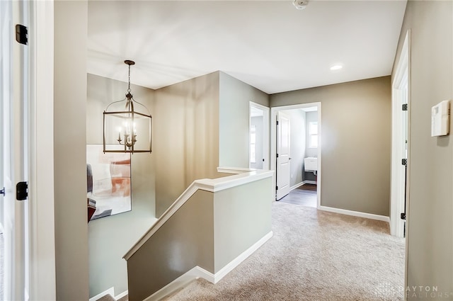 corridor with carpet flooring and an inviting chandelier