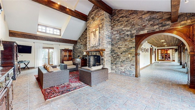 living room featuring beam ceiling, a fireplace, and high vaulted ceiling