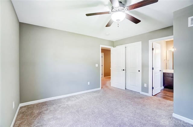 unfurnished bedroom featuring light carpet, connected bathroom, a closet, and ceiling fan