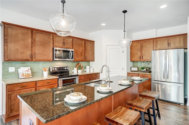 kitchen featuring sink, dark wood-type flooring, stainless steel appliances, tasteful backsplash, and decorative light fixtures