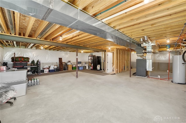 basement with water heater and black refrigerator