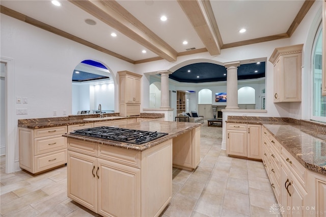 kitchen with beamed ceiling, stone counters, a center island, ornate columns, and gas stovetop