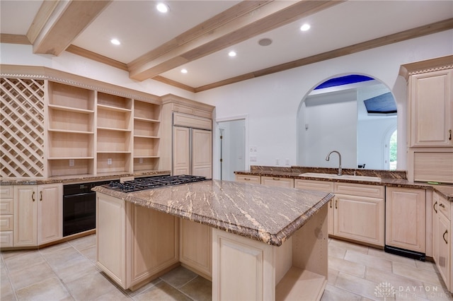 kitchen with light stone counters, beam ceiling, sink, and a kitchen island