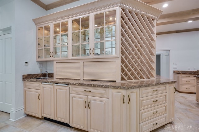 kitchen with ornamental molding, cream cabinets, stone counters, and sink