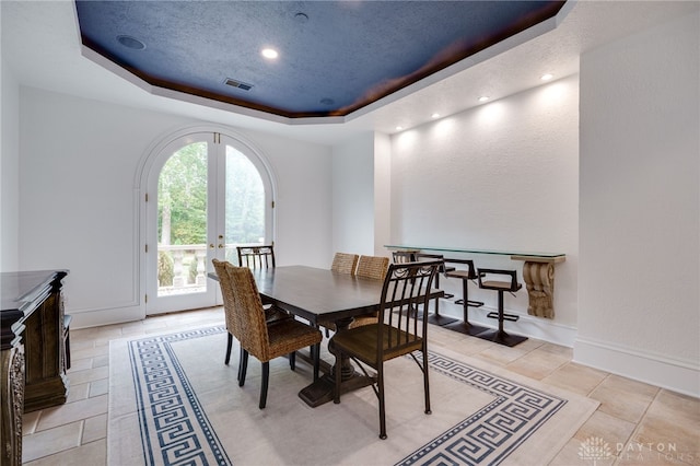 tiled dining area featuring a tray ceiling and french doors