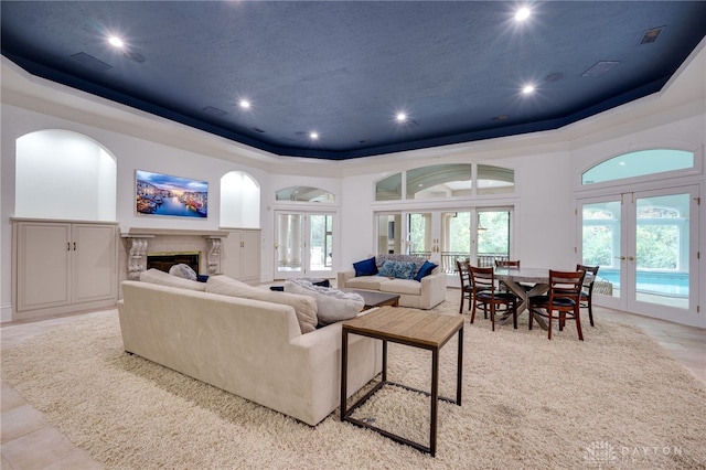 living room featuring a premium fireplace, a raised ceiling, light tile patterned floors, and french doors