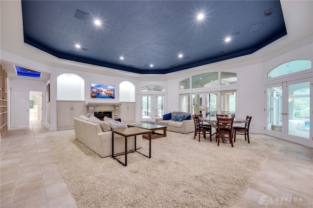 living room featuring french doors, a raised ceiling, and a wealth of natural light