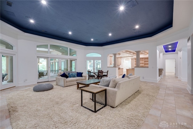 living room with french doors, light tile patterned floors, a raised ceiling, and ornate columns