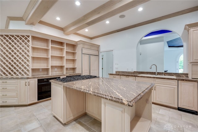 kitchen with light stone counters, a center island, sink, beam ceiling, and stainless steel gas cooktop