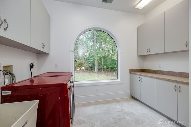 laundry room with cabinets, plenty of natural light, and separate washer and dryer