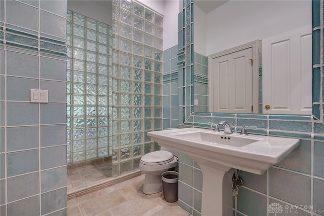 bathroom featuring a tile shower, tile walls, and toilet