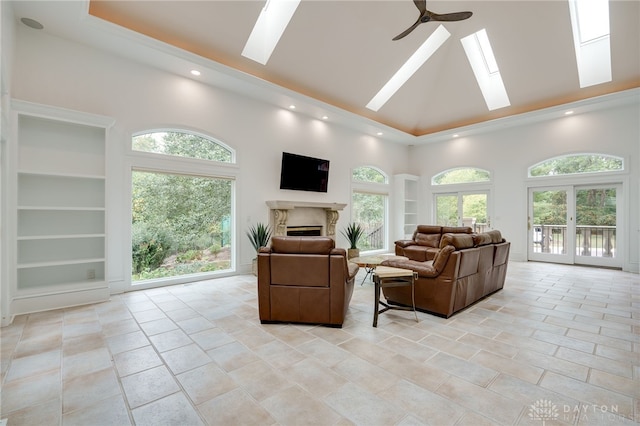 living room featuring a towering ceiling, a skylight, plenty of natural light, and ceiling fan