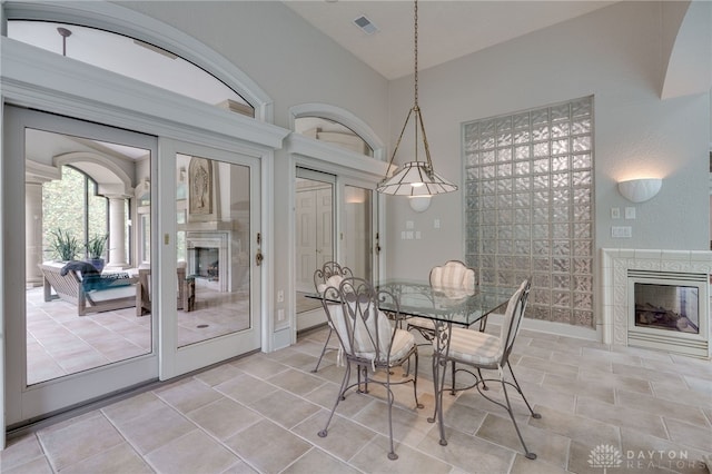 dining space with high vaulted ceiling, a premium fireplace, and french doors