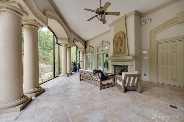 unfurnished living room with high vaulted ceiling, ornamental molding, decorative columns, and ceiling fan