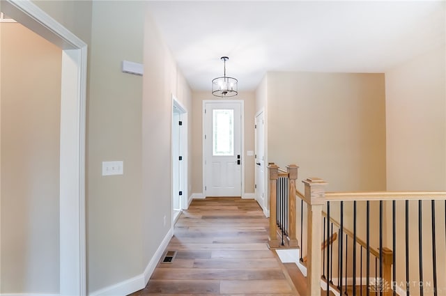 doorway to outside featuring an inviting chandelier and hardwood / wood-style flooring