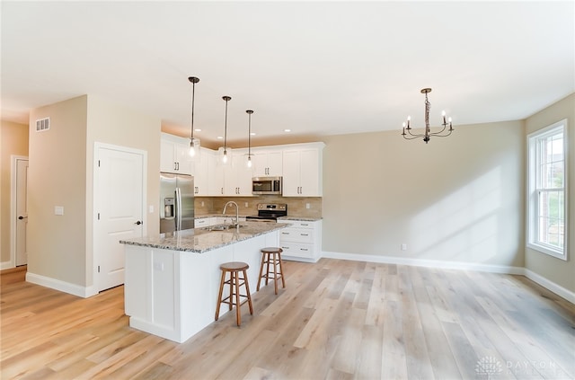 kitchen featuring stainless steel appliances, white cabinetry, light hardwood / wood-style floors, and stone counters