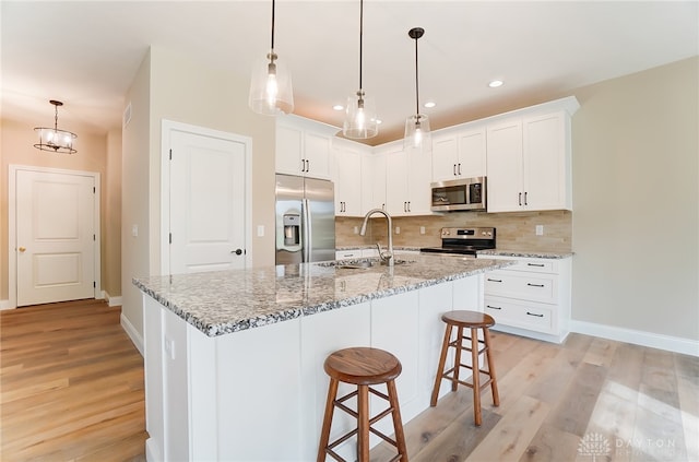 kitchen featuring light hardwood / wood-style flooring, stainless steel appliances, white cabinets, and an island with sink