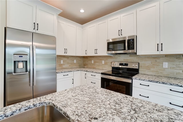 kitchen with decorative backsplash, white cabinetry, stainless steel appliances, and light stone counters