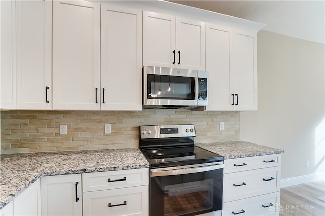 kitchen featuring white cabinets, light stone countertops, tasteful backsplash, stainless steel appliances, and light wood-type flooring