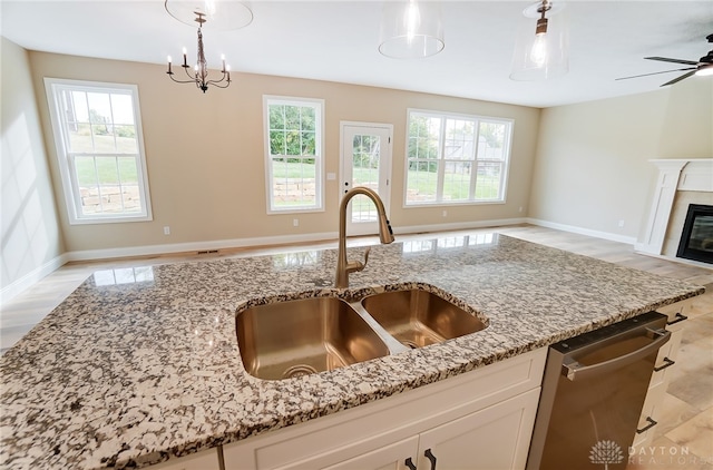 kitchen featuring a healthy amount of sunlight, white cabinets, sink, and light stone countertops