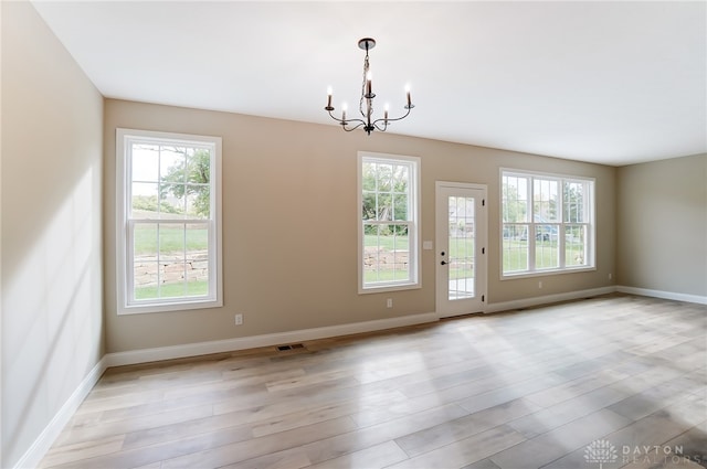 unfurnished room featuring light hardwood / wood-style floors and a notable chandelier