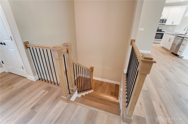 stairway featuring heating unit, hardwood / wood-style flooring, and sink