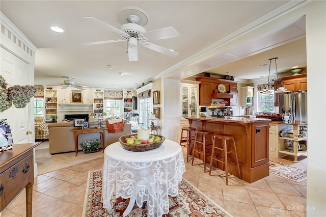 tiled dining space with ceiling fan, plenty of natural light, and crown molding