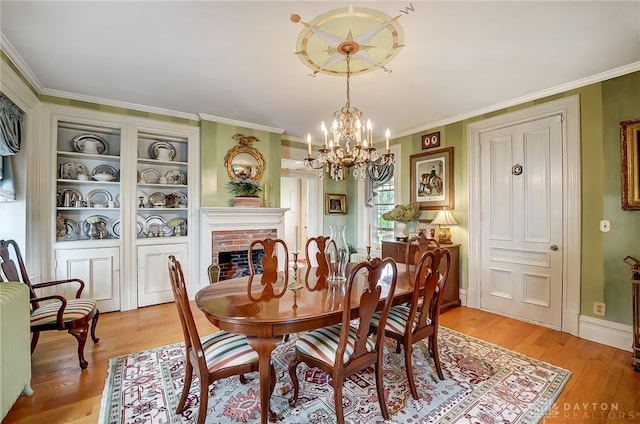 dining space featuring a notable chandelier, a fireplace, light wood-type flooring, and ornamental molding