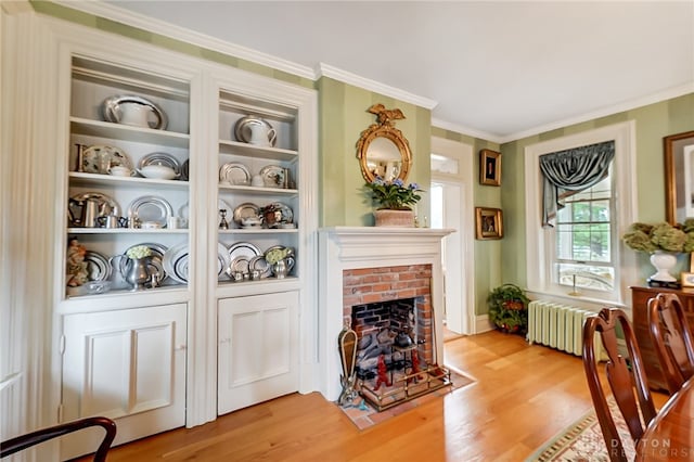 living room with wood-type flooring, a brick fireplace, crown molding, and radiator heating unit