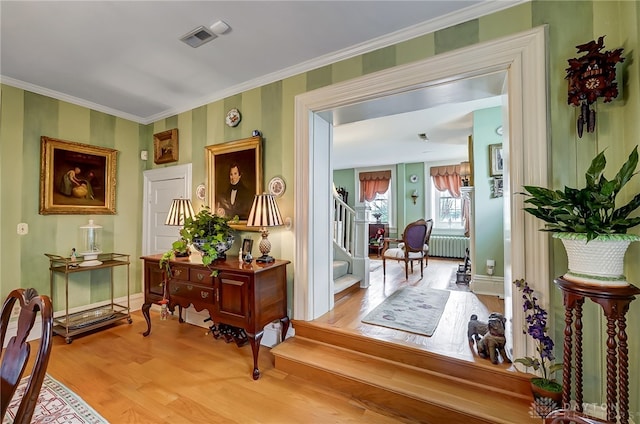 hallway with ornamental molding, light hardwood / wood-style floors, and radiator heating unit