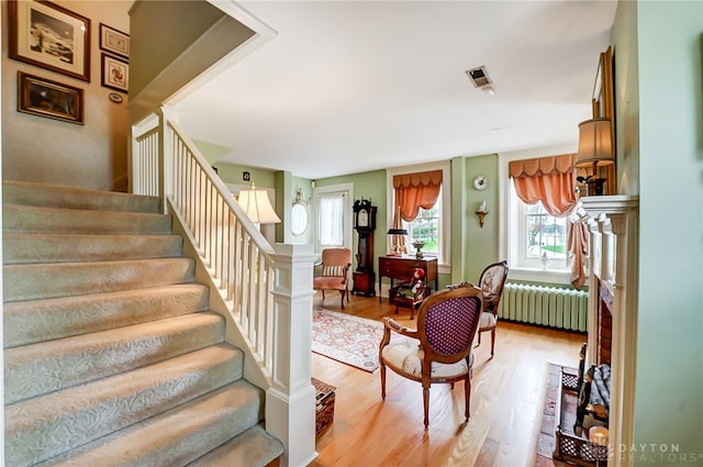 stairs featuring hardwood / wood-style floors and radiator heating unit