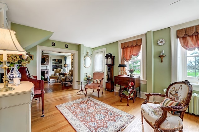 living area with radiator, hardwood / wood-style flooring, and a healthy amount of sunlight