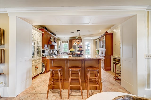 kitchen with crown molding, a kitchen island, a breakfast bar area, and pendant lighting