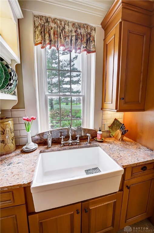 kitchen featuring decorative backsplash, light stone counters, and sink