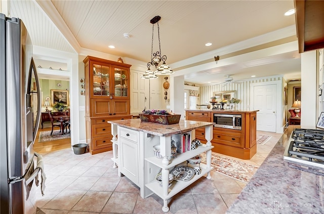 kitchen featuring light stone counters, white cabinets, a kitchen island, decorative light fixtures, and stainless steel appliances