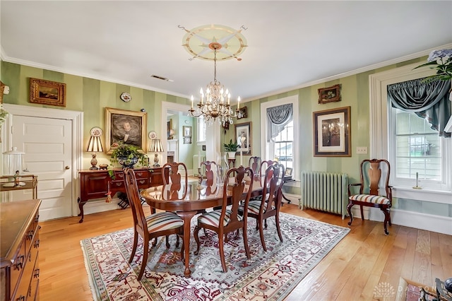 dining area with light hardwood / wood-style floors, radiator heating unit, and a healthy amount of sunlight