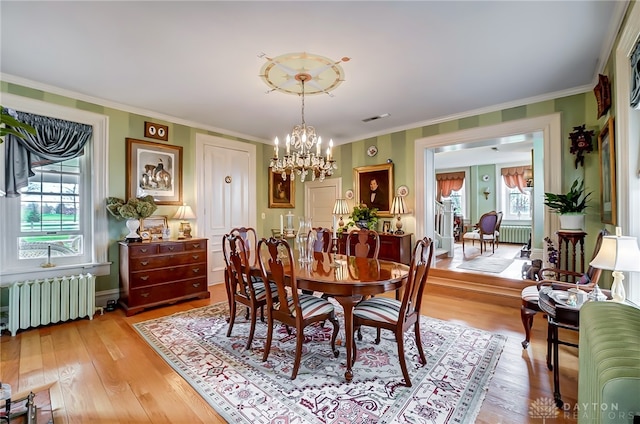 dining space with radiator heating unit, a notable chandelier, light hardwood / wood-style flooring, and plenty of natural light