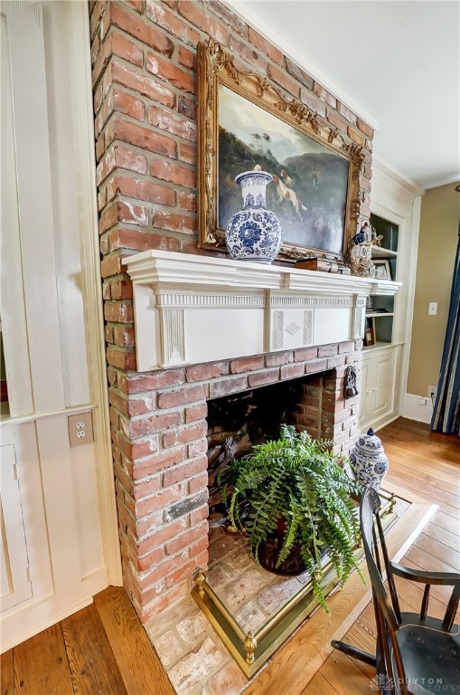 interior details with a brick fireplace, hardwood / wood-style flooring, and crown molding