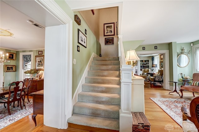 stairway featuring wood-type flooring and a notable chandelier