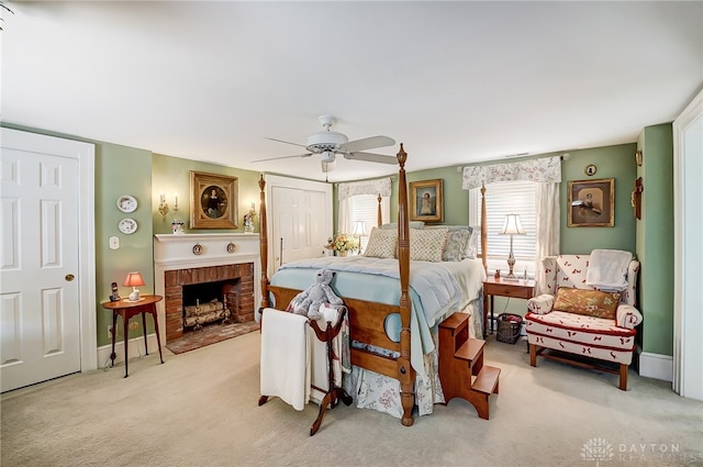 carpeted bedroom featuring ceiling fan and a fireplace