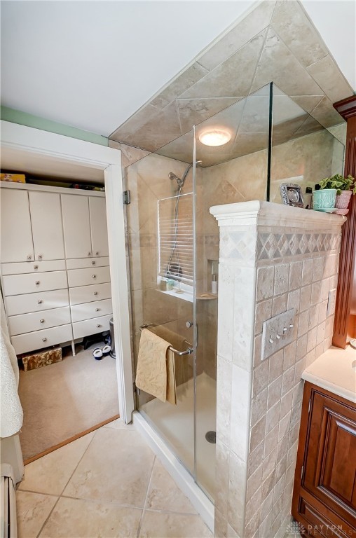 bathroom with tile walls, tile patterned flooring, vanity, and a shower with shower door