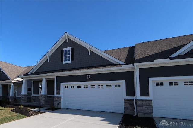 craftsman-style house with a porch, concrete driveway, an attached garage, and stone siding