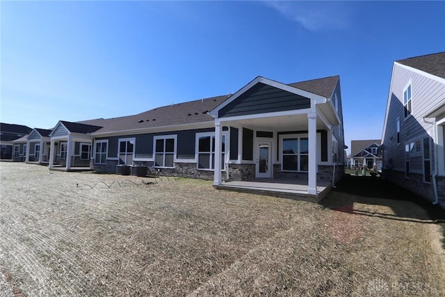 rear view of house featuring stone siding and a patio